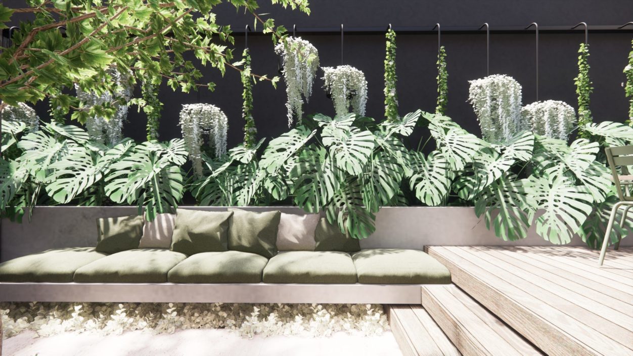 A landscape design of a layered planting with monsteras and pale decking